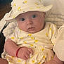 Cassandra is registered to the contest to win money with this photo: baby, infant, hat, clothing, yellow, lemon_pattern, cute, child, portrait, hand, face, eyes, indoors, soft_lighting, cozy, fabric, sitting, person, apparel, adorable