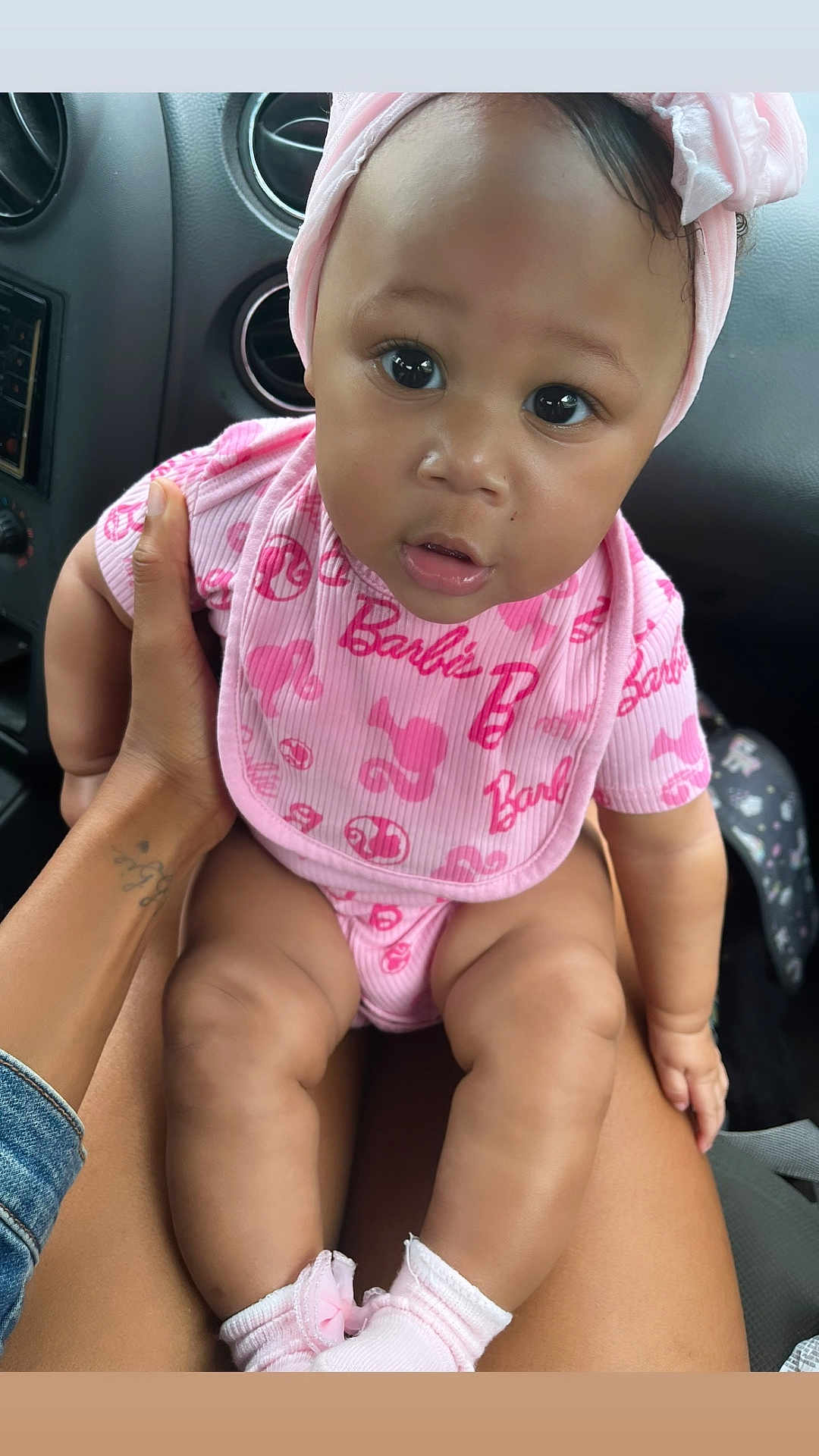 Anaee is registered to the contest to win money with this photo: baby, child, infant, pink_clothing, headwrap, car_interior, person, sitting, legs, hand, cute, looking_at_camera, closeup, adorable, sock, bib, human, seat, portrait, casual