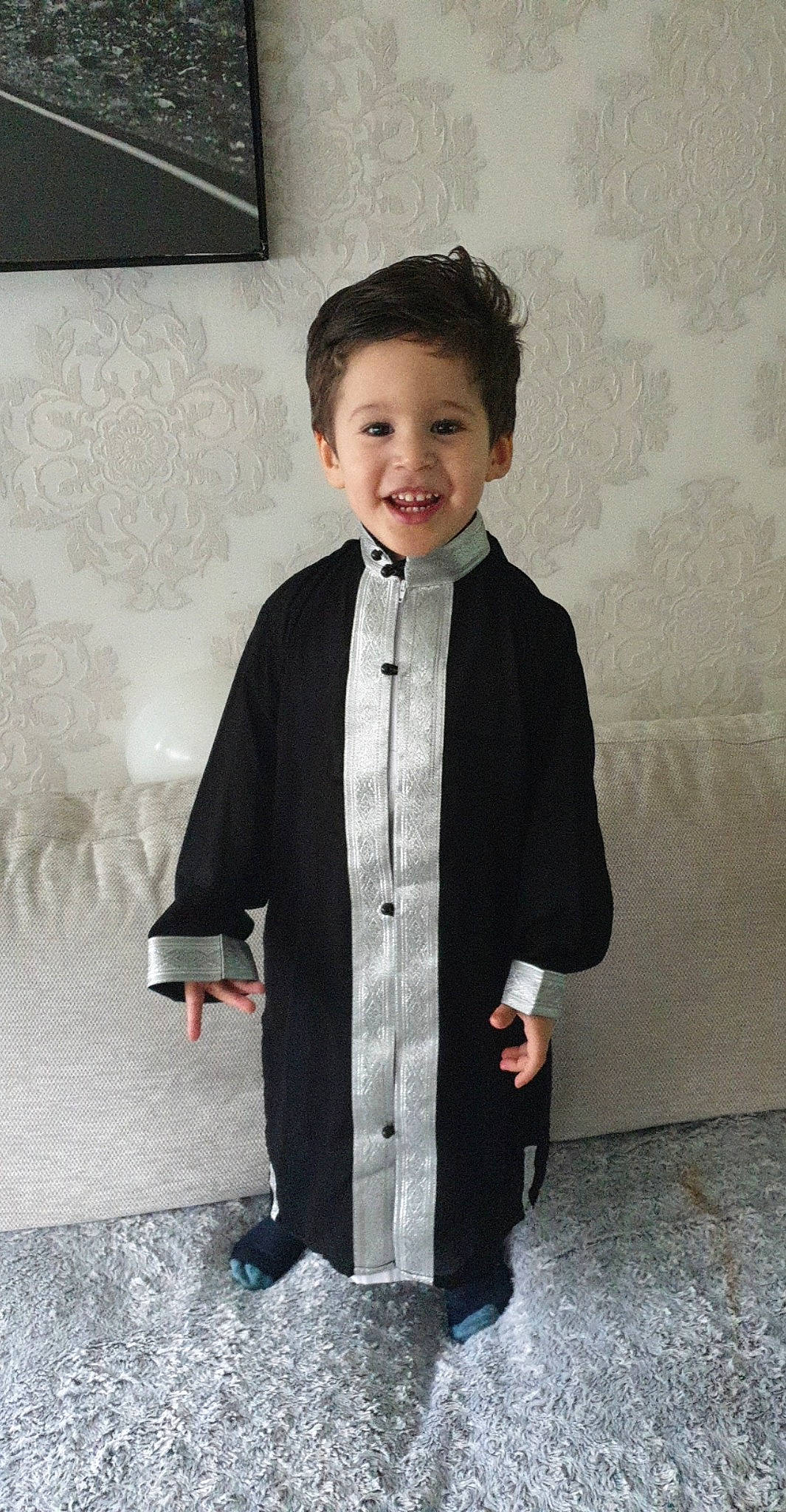 Moussa participe au concours pour gagner de l'argent avec cette photo : academic_dress, child, clothing, coat, formal_wear, joy, outerwear, person, smile, standing, suit, tie, tuxedo