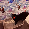 cat, black_cat, pet, animal, indoors, litter_box, litter, tail, wide_eyes, red_toy, winter, snow, reindeer, wallpaper, storybook, fairytale, bathroom, tile_floor, doormat, holiday