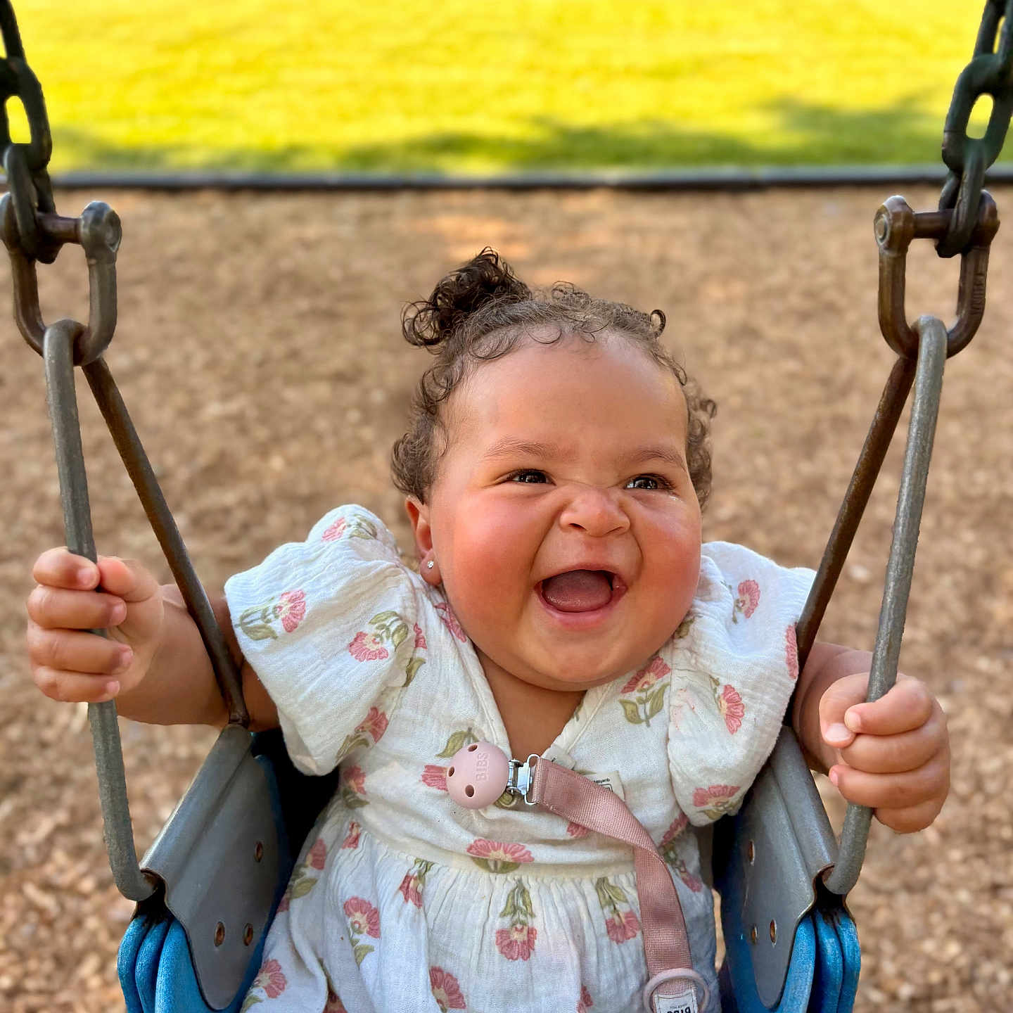Nariah joined the competition — help win amazing prizes! baby, chains, child, curly_hair, cute, dress, happy, infant, joyful, nature, outdoor, pacifier, park, person, playground, seat, smiling, sunlight, swing, wood_chips