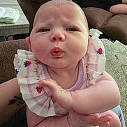 Amelia is registered to the contest to win money with this photo: baby, infant, child, cute, pucker, face, expression, indoor, clothing, strawberry, pattern, arm, hand, person, couch, carpet, furniture, skin, young, closeup