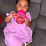 Zalaya is registered to the contest to win money with this photo: toddler, child, sippy_cup, purple_dress, white_sandals, couch, indoor, baby_hair, hair_clips, curly_hair, sitting, drinking, cute, portrait, young_child, brown_skin, big_eyes, clothing, footwear, furniture