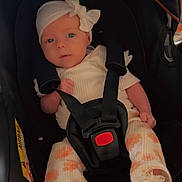 Phoebe joined the competition — help win amazing prizes! baby, infant, car_seat, headband, bow, white_clothing, orange_flower_pattern, socks, straps, black_car_seat, child, cute, indoors, portrait, small_hands, small_feet, seatbelt, looking_at_camera, soft_lighting, young_child