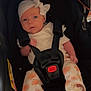 baby, infant, car_seat, headband, bow, white_clothing, orange_flower_pattern, socks, straps, black_car_seat, child, cute, indoors, portrait, small_hands, small_feet, seatbelt, looking_at_camera, soft_lighting, young_child
