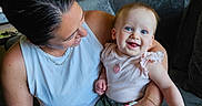 Hazel joined the competition — help win amazing prizes! baby, child, woman, smile, happy, indoor, couch, blue_eyes, holding, casual_clothing, home, portrait, seated, parent, love, skin, furniture, tattoo, bracelet, shorts
