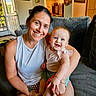 Hazel is registered to the contest to win money with this photo: woman, baby, smile, happy, couch, indoor, home, furniture, person, child, portrait, living_room, casual, seated, clothing, face, arm, skin, decor, tattoo