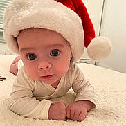 Ugo participe au concours pour gagner de l'argent avec cette photo : baby, infant, santa_hat, holiday, cute, soft_blanket, indoors, child, face, wide_eyes, white_clothing, portrait, close_up, festive, christmas, smiling, young_child, resting, cozy, cute_expression