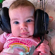 Rosetta joined the competition — help win amazing prizes! baby, headphones, pink_shirt, rainbow, microphone, child, face, expression, curious, animal_pattern, background, hand, clothing, infant, cute, indoor, portrait, closeup, person, technology
