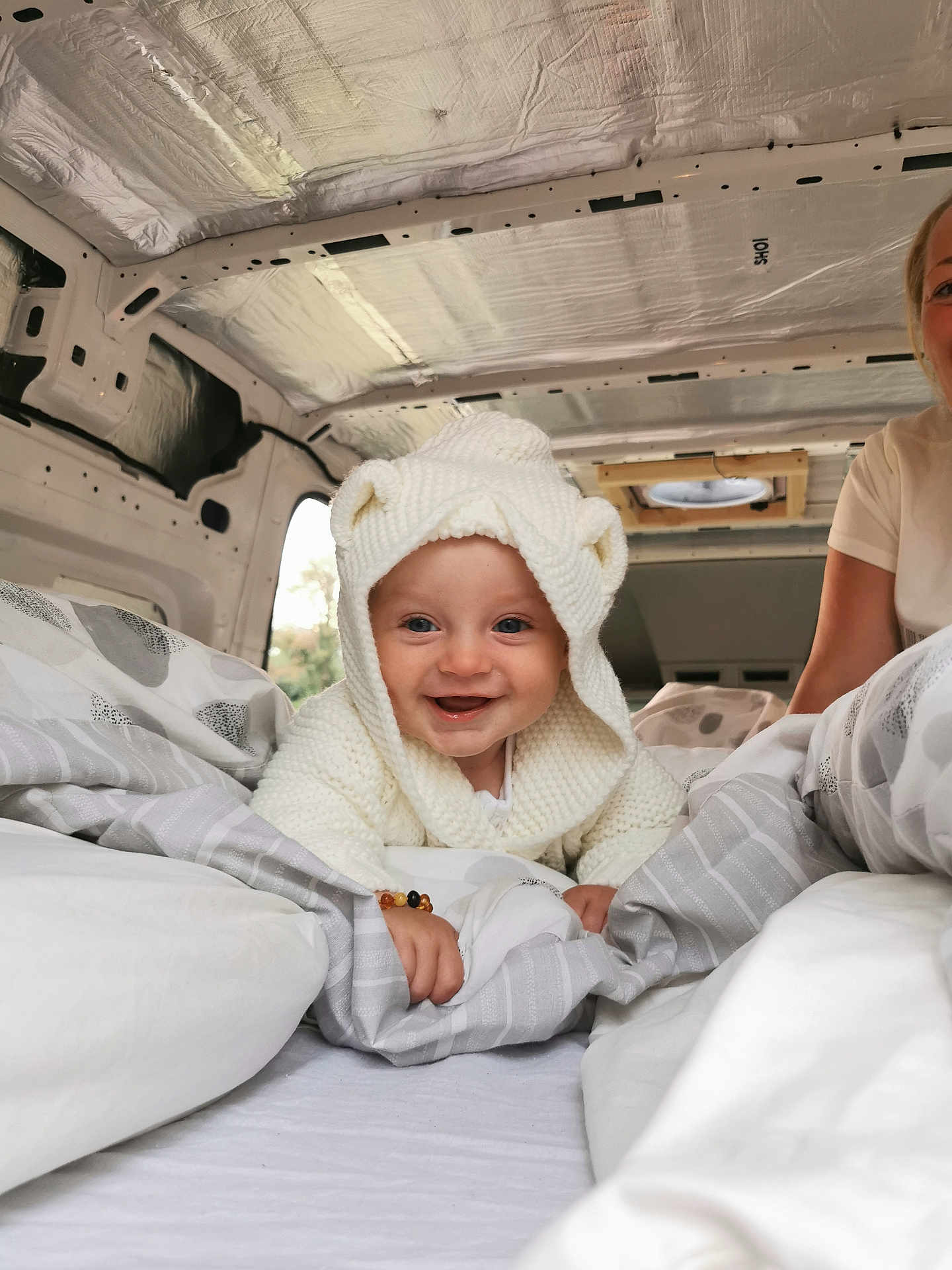 Rory is registered to the contest to win money with this photo: baby, child, smile, hoodie, knitwear, blanket, bed, van, interior, person, happy, cute, cozy, white, face, portrait, indoor, travel, comfort, candid