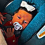 Kensley-May is registered to the contest to win money with this photo: baby, pacifier, car_seat, blue_cushion, white_bow, red_clothing, infant, child, face, hand, safety_warning, seatbelt, blanket, closeup, indoors, cute, portrait, young_child, headwear, resting