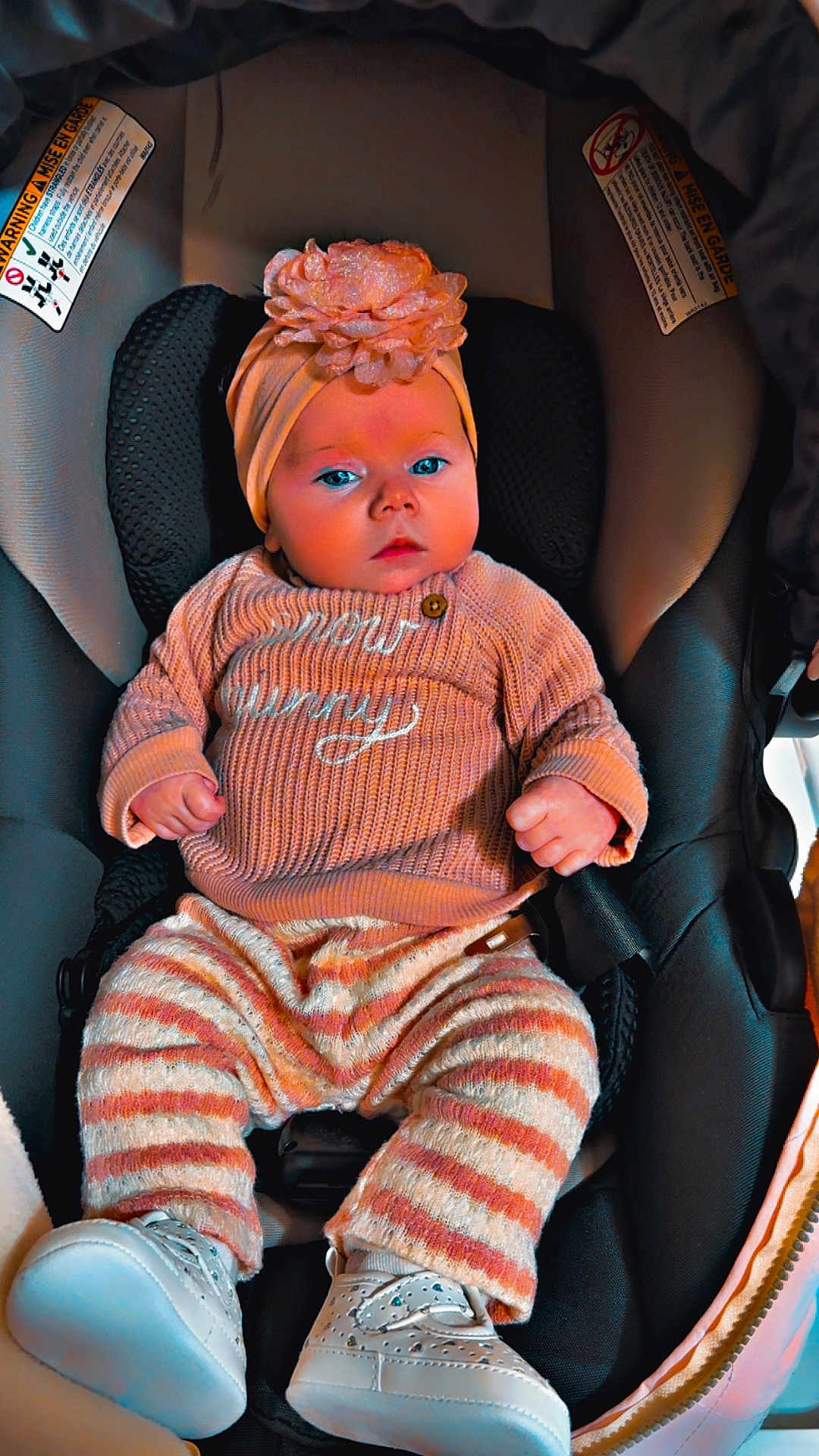 Kensley-May joined the competition — help win amazing prizes! baby, child, car_seat, headband, flower, striped_pants, knitted_sweater, white_shoes, cozy, infant, seated, clothing, cute, portrait, indoor, comfortable, face, hands, footwear, baby_accessory
