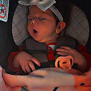 Kensley-May is registered to the contest to win money with this photo: baby, car_seat, bow, blanket, pacifier, infant, child, headband, clothing, hand, face, cute, sleepy, indoors, person, comfort, soft_light, expression, seat_belt, toddler