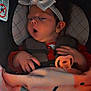 baby, car_seat, bow, blanket, pacifier, infant, child, headband, clothing, hand, face, cute, sleepy, indoors, person, comfort, soft_light, expression, seat_belt, toddler