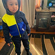 Demari joined the competition — help win amazing prizes! child, toddler, hoodie, clothing, indoor, carpet, curtains, furniture, television, cabinet, person, socks, floor, expression, standing, room, home, casual, portrait, young