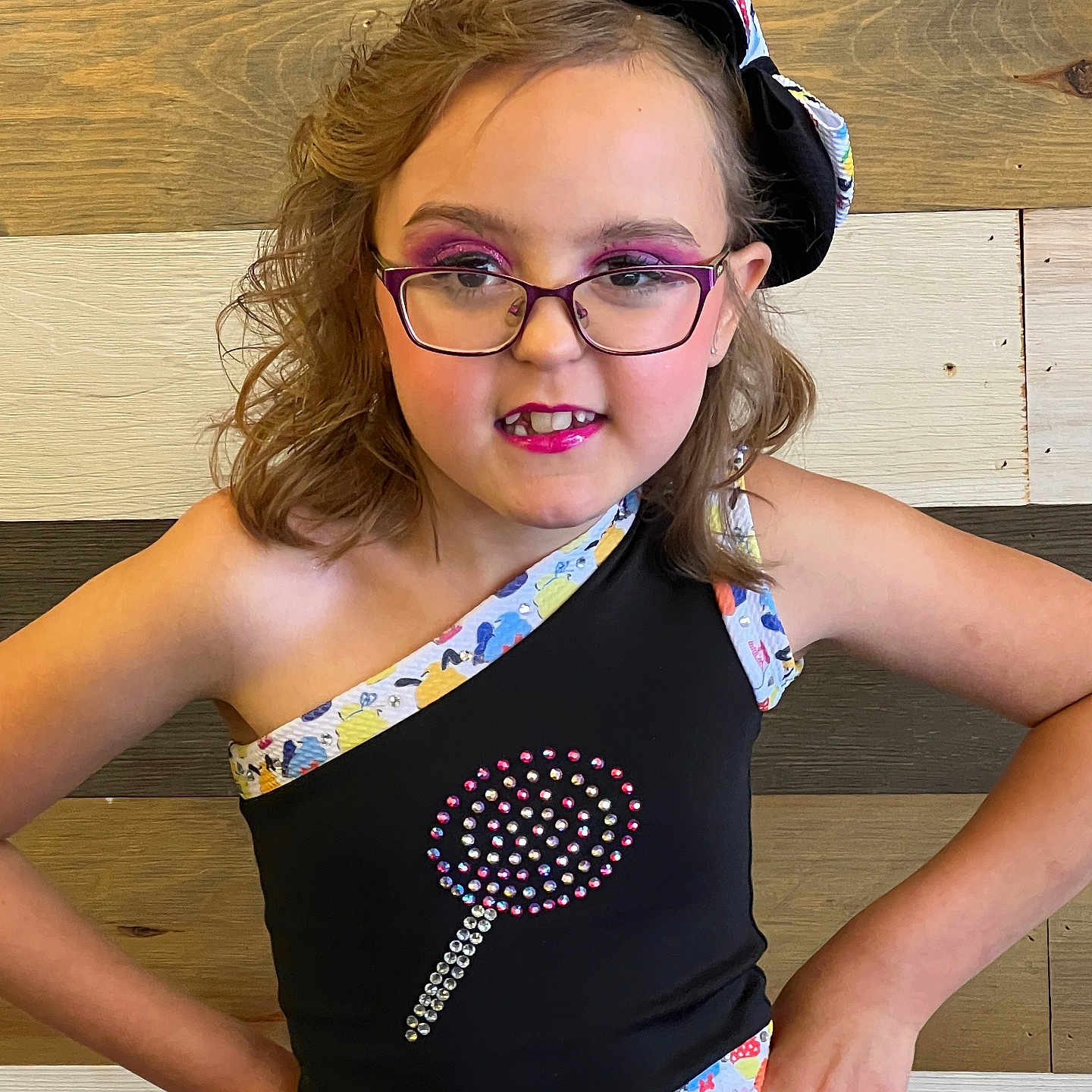 Kiara is registered to the contest to win money with this photo: accessories, applique, blouse, bodypart, child, clothing, dress, face, female, finger, girl, glasses, hand, head, pattern, person, photography, portrait, t_shirt, wood