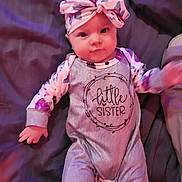 Everleigh joined the competition — help win amazing prizes! baby, infant, child, headband, bow, onesie, text_on_clothing, blanket, bedding, portrait, eyes, hands, cheeks, clothing, floral_pattern, pink_tones, purple_tones, lying_down, adorable, sibling_announcement