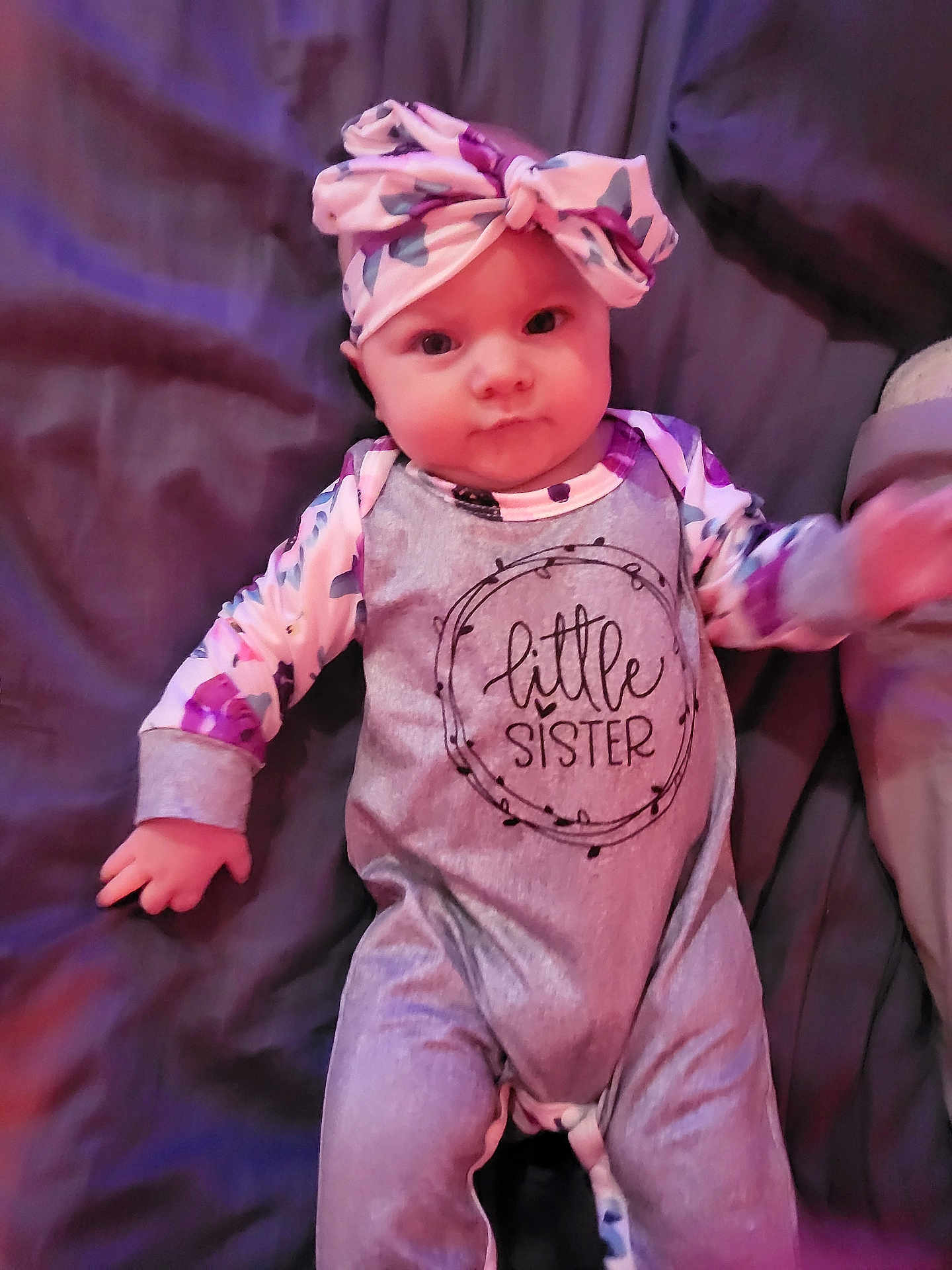 Everleigh joined the competition — help win amazing prizes! baby, infant, child, headband, bow, onesie, text_on_clothing, blanket, bedding, portrait, eyes, hands, cheeks, clothing, floral_pattern, pink_tones, purple_tones, lying_down, adorable, sibling_announcement