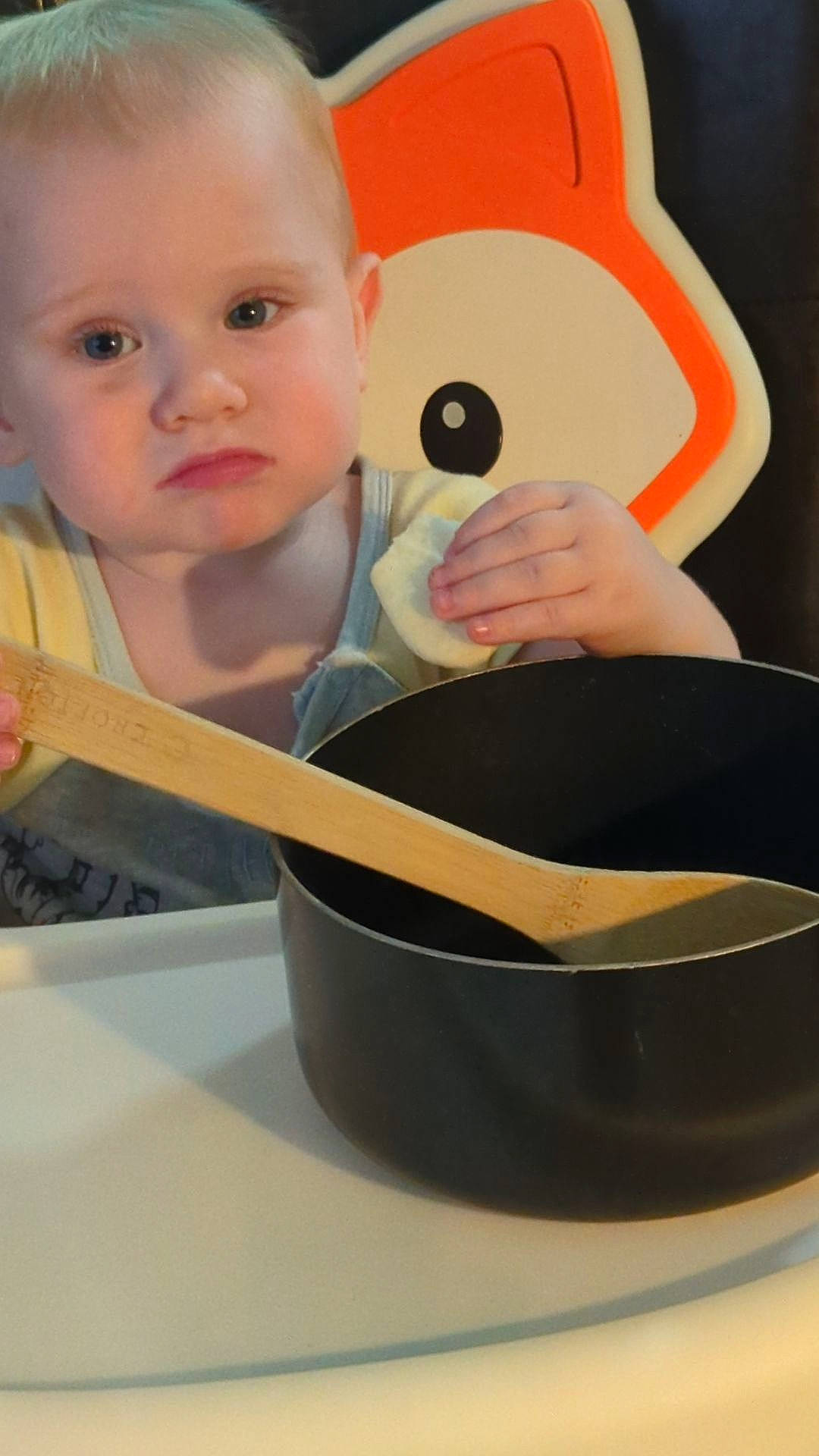 Spencer is registered to the contest to win money with this photo: audio_equipment, baby, baby_toddler_clothing, carmine, chair, cheek, child, drinkware, ear, elbow, eyelash, finger, person, room, serveware, sitting, sleeve, t_shirt, table, tableware