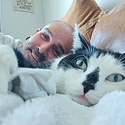 Guilford is registered to the contest to win money with this photo: blanket, cat, close_up, comfort, couch, cozy, face, friendship, fur, furniture, home, human, indoor, man, nose_ring, pet, portrait, relaxed, smiling, whiskers