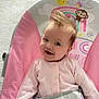 baby, infant, child, smiling, pink_clothing, baby_seat, monkey_graphic, sun_graphic, rainbow_graphic, hair_spiky, drool, happy, cute, indoors, seat_belt, patterned_fabric, colorful, portrait, sitting, young_child