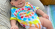 Leo joined the competition — help win amazing prizes! baby, child, outdoor, tie_dye, onesie, cap, hat, picnic, basket, cushion, striped, blanket, grass, smiling, happy, relaxed, infant, person, casual, colorful