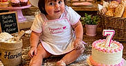 Georgina is registered to the contest to win money with this photo: child, toddler, baby, baker, chef_hat, apron, birthday_cake, number_seven, flour, baking, bakery, cupcakes, bread, pastries, kitchen, pink_mixer, roses, wooden_table, sitting, portrait