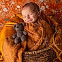 newborn, baby, sleeping, blanket, basket, knitted_toy, teddy_bear, cozy, brown, orange, floral_pattern, portrait, cute, peaceful, infant, wrapped, soft_texture, homedecor, photography, studio