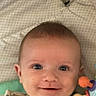 John is registered to the contest to win money with this photo: baby, blanket, child, closeup, clothing, cute, expression, eyes, face, happy, head, indoors, infant, lying_down, pattern, person, play, skin, smile, toy