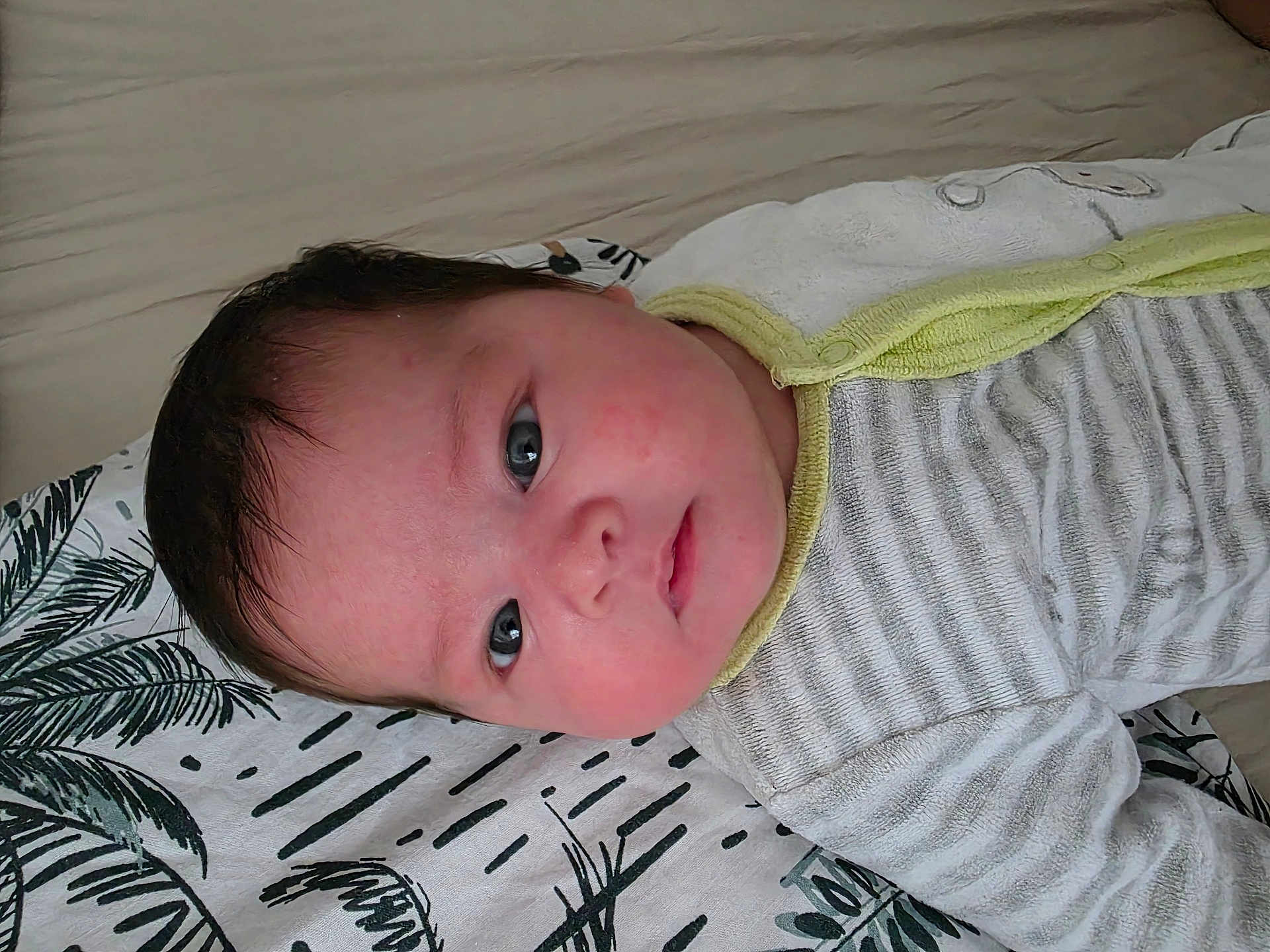 Amelia participe au concours pour gagner de l'argent avec cette photo : baby, infant, face, blue_eyes, striped_clothing, onesie, blanket, pattern, lying_down, curious, closeup, head, cheeks, young_child, indoor, soft_light, skin, hair, expression, resting