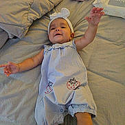 Zoey joined the competition — help win amazing prizes! baby, infant, bed, blanket, clothing, headband, arm, smile, cute, romper, strawberry_print, baby_wipes, fabric, person, child, indoor, soft_light, reaching, comfort, toddler