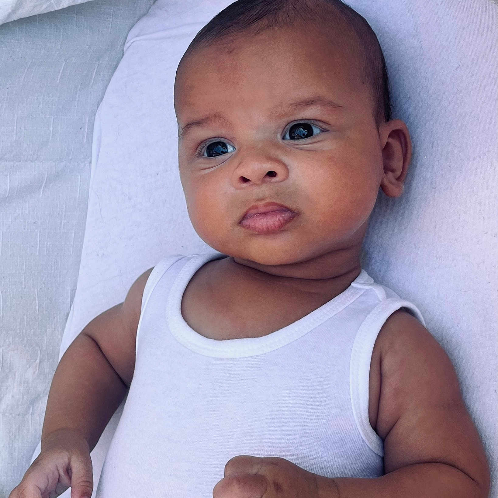 Soël a rejoint le concours — aidez-le/la à gagner de superbes lots ! adorable, arm, baby, blanket, child, closeup, curious_eyes, cute, expression, hand, indoor, infant, lying_down, newborn, peaceful, person, portrait, skin, soft_light, white_tank_top