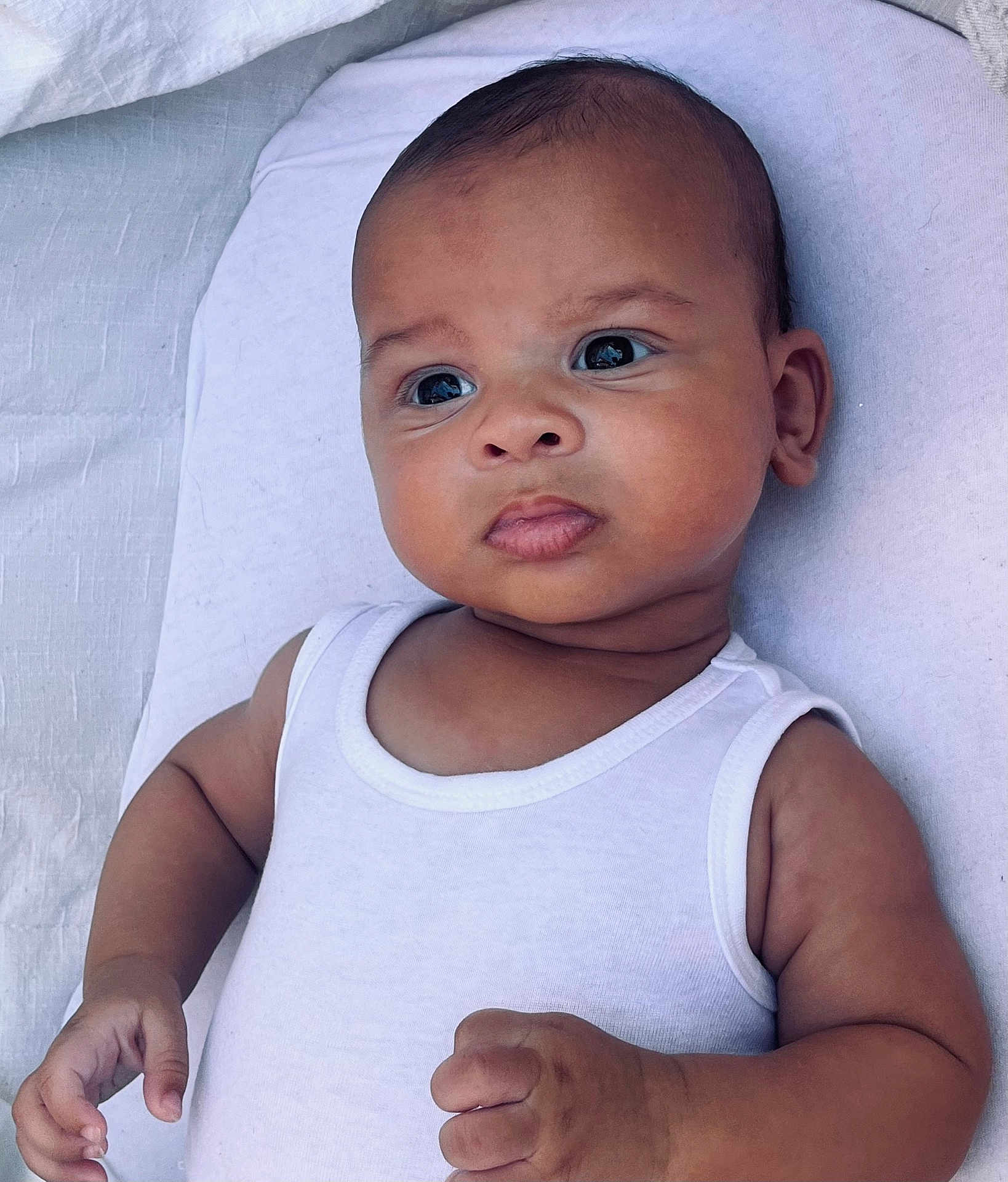 Soël a rejoint le concours — aidez-le/la à gagner de superbes lots ! baby, infant, child, white_tank_top, blanket, lying_down, curious_eyes, skin, arm, hand, portrait, closeup, cute, indoor, soft_light, expression, person, newborn, peaceful, adorable