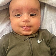 Rovan joined the competition — help win amazing prizes! baby, infant, child, portrait, face, eyes, looking_at_camera, lying_down, onesie, clothing, olive_green, nike_logo, blanket, bedding, soft_lighting, indoors, close_up, adorable, neutral_expression, head