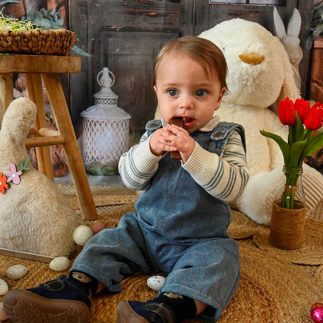 Victor participe au concours pour gagner de l'argent avec cette photo : toddler, child, denim_overalls, striped_sweater, chocolate, easter_eggs, plush_bunny, stuffed_animal, woven_rug, wooden_stool, vase, red_tulips, rustic_door, indoor, floor, cute, curious, sitting, toy, holiday
