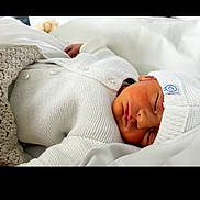 Swann a rejoint le concours — aidez-le/la à gagner de superbes lots ! newborn, baby, sleeping, white_clothing, knitwear, hat, blanket, soft, peaceful, infant, cute, resting, portrait, indoors, closeup, cozy, child, person, warm, comfort