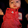 baby, infant, overalls, red_stripes, clothing, face, portrait, cute, child, blue_eyes, skin, head, expression, young, person, dark_background, button, patch, casual_wear, closeup