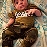 Daylan is registered to the contest to win money with this photo: baby, infant, child, camo_clothing, hat, pacifier, blanket, lying_down, cute, face, expression, soft_texture, patterned_blanket, small_hands, clothing, indoors, portrait, young_child, toddler, resting