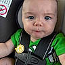 baby, infant, car_seat, seat_belt, green_shirt, blue_eyes, close_up, child, straps, expression, face, person, young, cute, sitting, indoor, safety, clothing, portrait, skin
