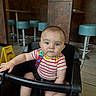 baby, child, high_chair, striped_shirt, blue_eyes, indoor, diner, bar_stools, floor_sign, caution_sign, pacifier_clip, person, infant, seat, foot, hand, tile_floor, wall, furniture, casual