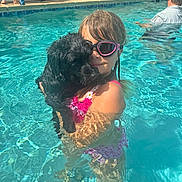 Candi Cortina joined the competition — help win amazing prizes! adult, background, black_dog, child, dog, fun, goggles, hugging, legs, outdoor, people, pink_swimsuit, playful, poolside, reflection, summer, sunlight, swimming_pool, water, water_splash