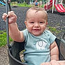 baby, child, swing, playground, smiling, elephant_print, shirt, hand, outdoor, grass, slide, play_equipment, metal_chain, happy, young_child, daylight, park, person, nature, fun