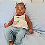 baby, child, infant, bed, blue_bedspread, colorful_hair_ties, jeans, white_top, pacifier, bare_feet, relaxed, indoors, person, cute, casual_clothing, portrait, young_child, skin, hand, face