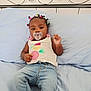 baby, child, pacifier, jeans, bed, blue_bed, hair_ties, infant, casual_clothing, cute, indoors, portrait, relaxing, young_child, person, sleeping_area, metal_bed_frame, colorful, infant_fashion, smiling