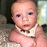 baby, blue_eyes, close_up, curious, face, infant, patterned_blanket, pale_skin, portrait, reaching_out, resting_arms, soft_background, toddler, young_child, wearing_clothing, indoor, expression, chubby_arms, head, skin_texture