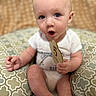 Kendall is registered to the contest to win money with this photo: baby, infant, child, milestone_card, blue_eyes, cushion, pattern, sitting, surprised_expression, onesie, hand, foot, skin, indoor, closeup, cute, young, person, portrait, soft_lighting