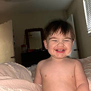 Sebastian joined the competition — help win amazing prizes! toddler, child, smiling, happy, indoor, bed, blanket, shirtless, face, hair, room, mirror, door, window, curtain, furniture, skin, expression, light, cozy