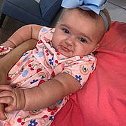Avery is registered to the contest to win money with this photo: baby, child, blue_bow, dress, indoor, person, arm, chair, toilet, bathroom, colorful_clothing, smiling, cute, headband, furniture, holding, closeup, skin, infant, portrait