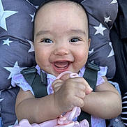 Aurora joined the competition — help win amazing prizes! baby, smiling, teething_toy, infant, happy, face, hand, clothing, seatbelt, cushion, star_pattern, closeup, child, baby_girl, cute, person, indoors, head, skin, toy