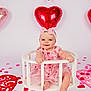 Gracie joined the competition — help win amazing prizes! baby, child, heart_balloon, pink_dress, headband, rose_petals, valentine_theme, white_background, smiling, sitting, circular_frame, cute, infant, decorations, studio_photo, playful, red_hearts, adorable, portrait, celebration